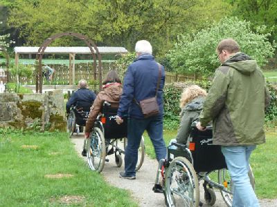 Rollifahrer in Begleitung besuchen Garten