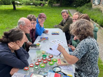 Gruppe von Menschen an einem Tisch mit Becherlupen und Bestimmungsbüchern