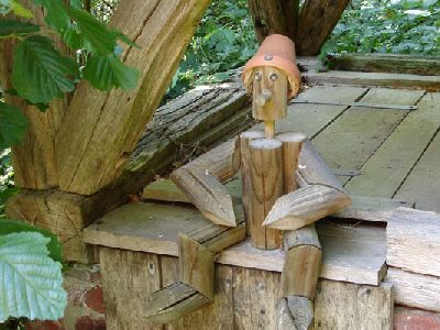 Auf Brunnen sitzendes Holzmännchen